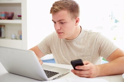 Adolescente utilizando el ordenador y el móvil